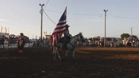 rider carrying an american flag during a rodeo event