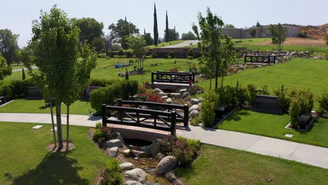 low rising aerial shot of small stream running through the manicured private estates gravesites at a mortuary in california