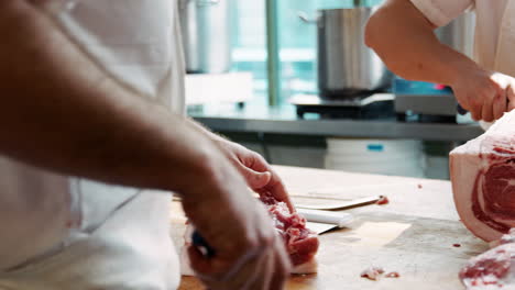 Two butchers cutting meat at a butcher&#039;s shop, mid section