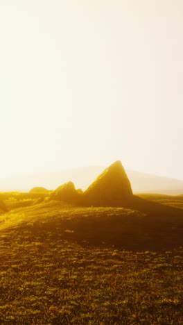 a beautiful landscape of a field with hills in the background, with the sun setting over the horizon