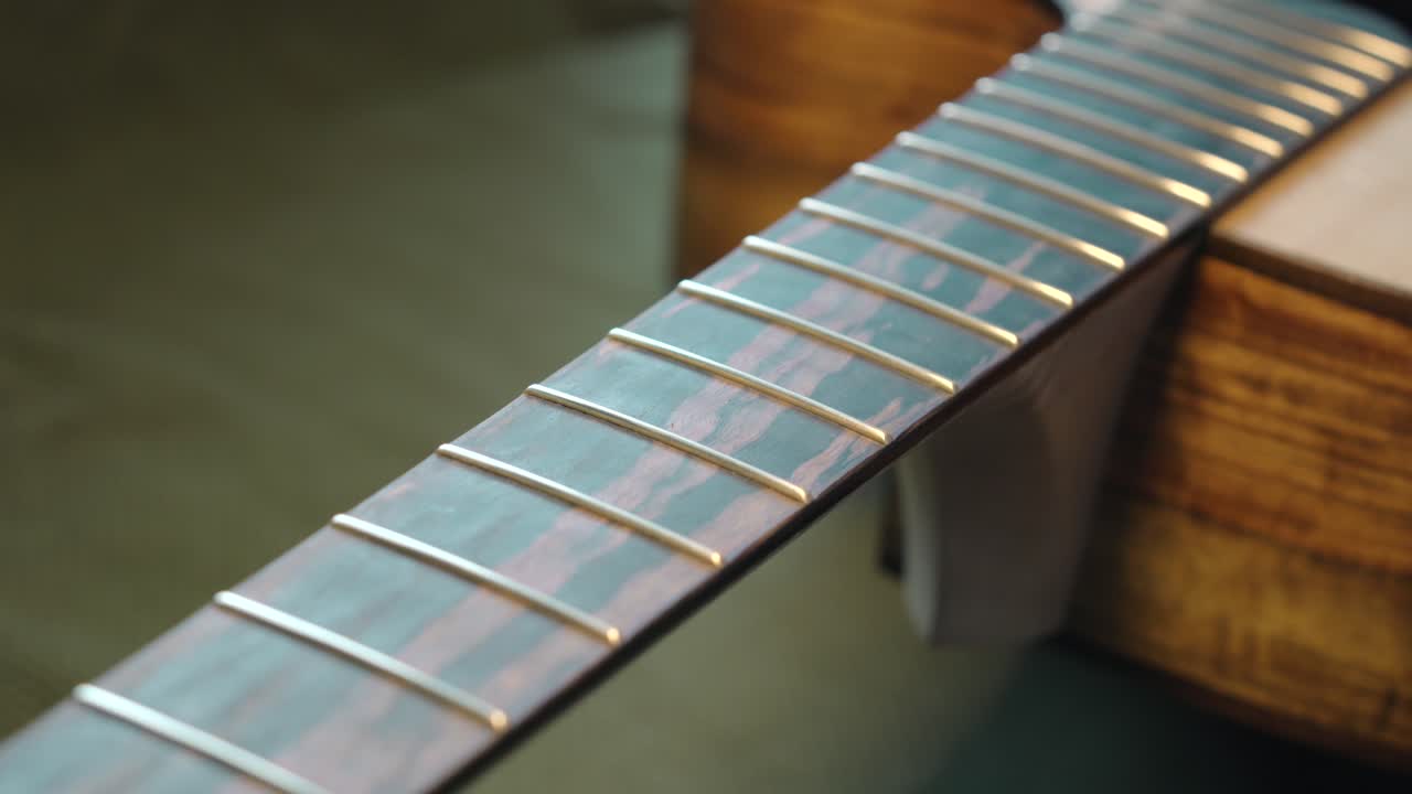 primer plano de trastes brillantes de una guitarra acústica después de pulir