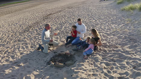 Drone-Shot-Of-Multi-Generation-Family-Having-Evening-Barbecue-Around-Fire-On-Beach-Vacation
