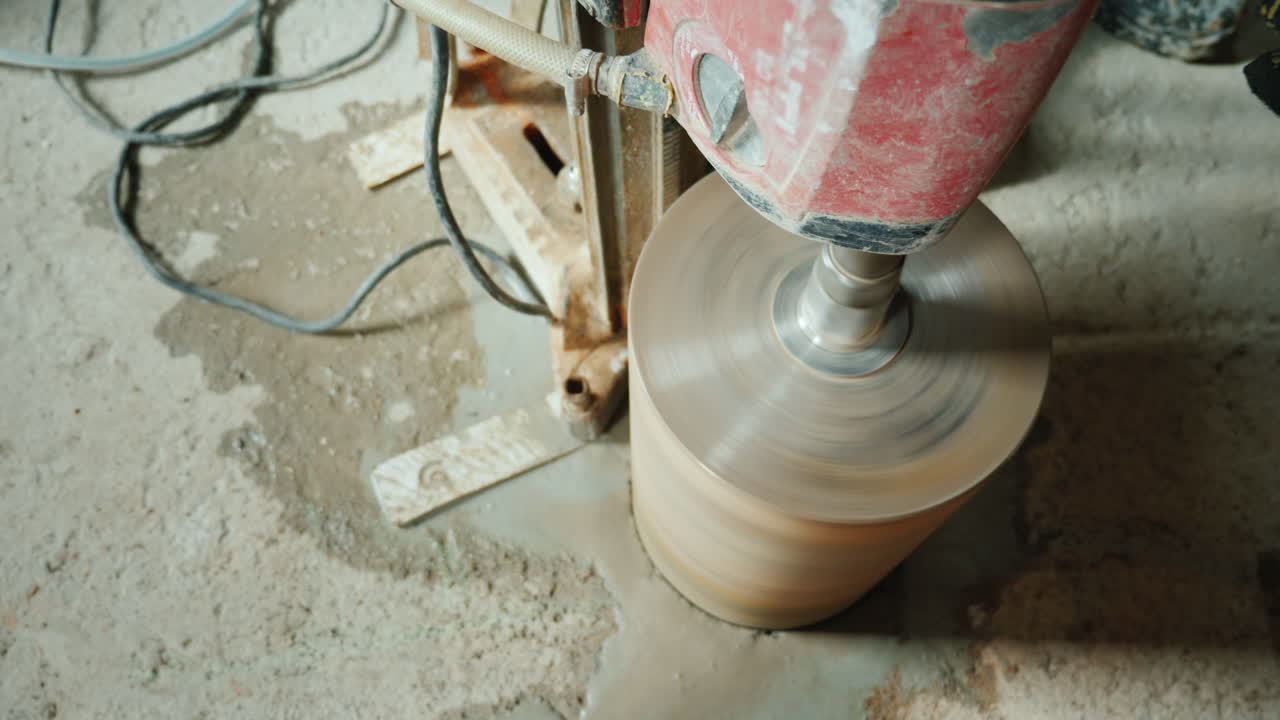 строитель сверлит отверстия в бетонном занавесе для прокладки вентиляционных труб и водопровода