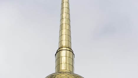 golden church spire against a cloudy sky