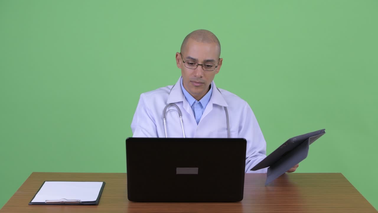 hombre multiétnico calvo estresado médico en el escritorio de la oficina