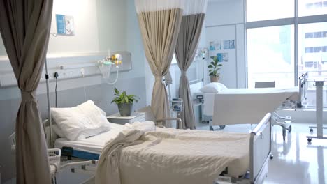 habitación de hospital soleada con camas, plantas y cortinas beige, cámara lenta