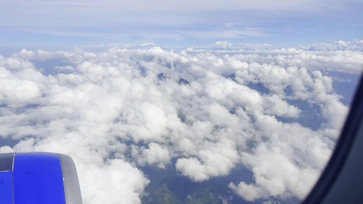 Optagelser, der viser skyer på himlen set fra et flyvindue, som fanger luftbårne atmosfæriske udsigter, bløde hvide formationer og en fredfyldt blå horisont, ideel til rejser, luftfart og visuelle naturelementer.