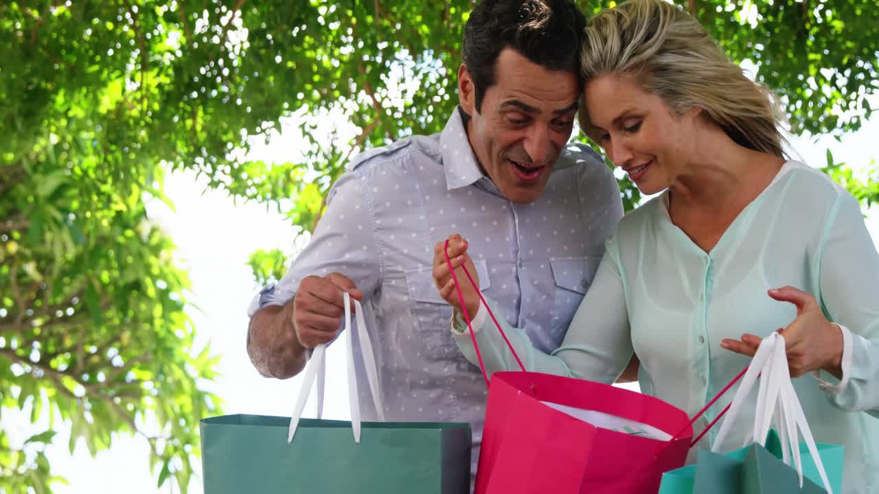 pareja sorprendida mirando en la bolsa de compras en un día soleado