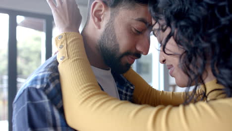 happy biracial couple embracing and smiling at home, in slow motion