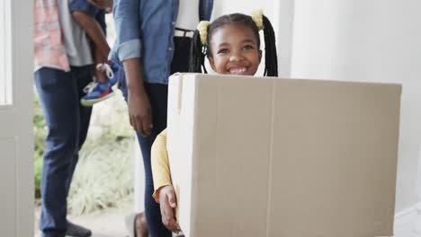 happy african american couple with son and daughter bringing boxes into house, slow motion