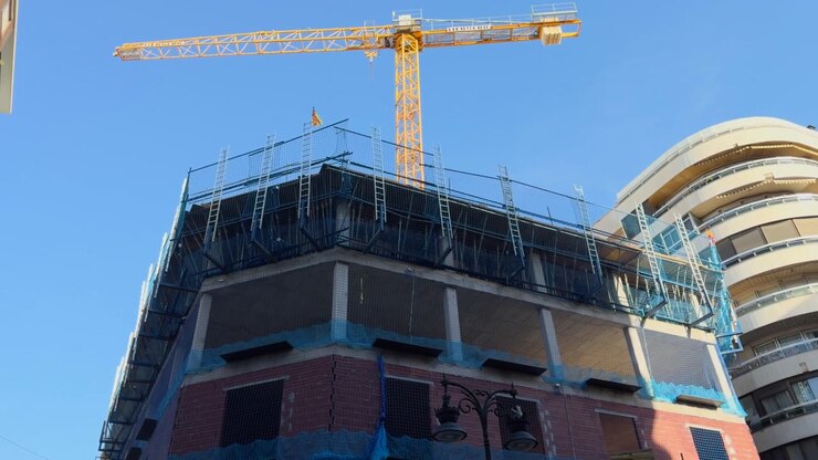 Industrial tower crane working at a construction site, building new structures and developing urban real estate.