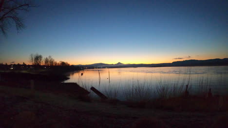 time lapse of a beautiful scenery of a large lake with a boat passing by, surrounded by large meadow and a beautiful blue sky