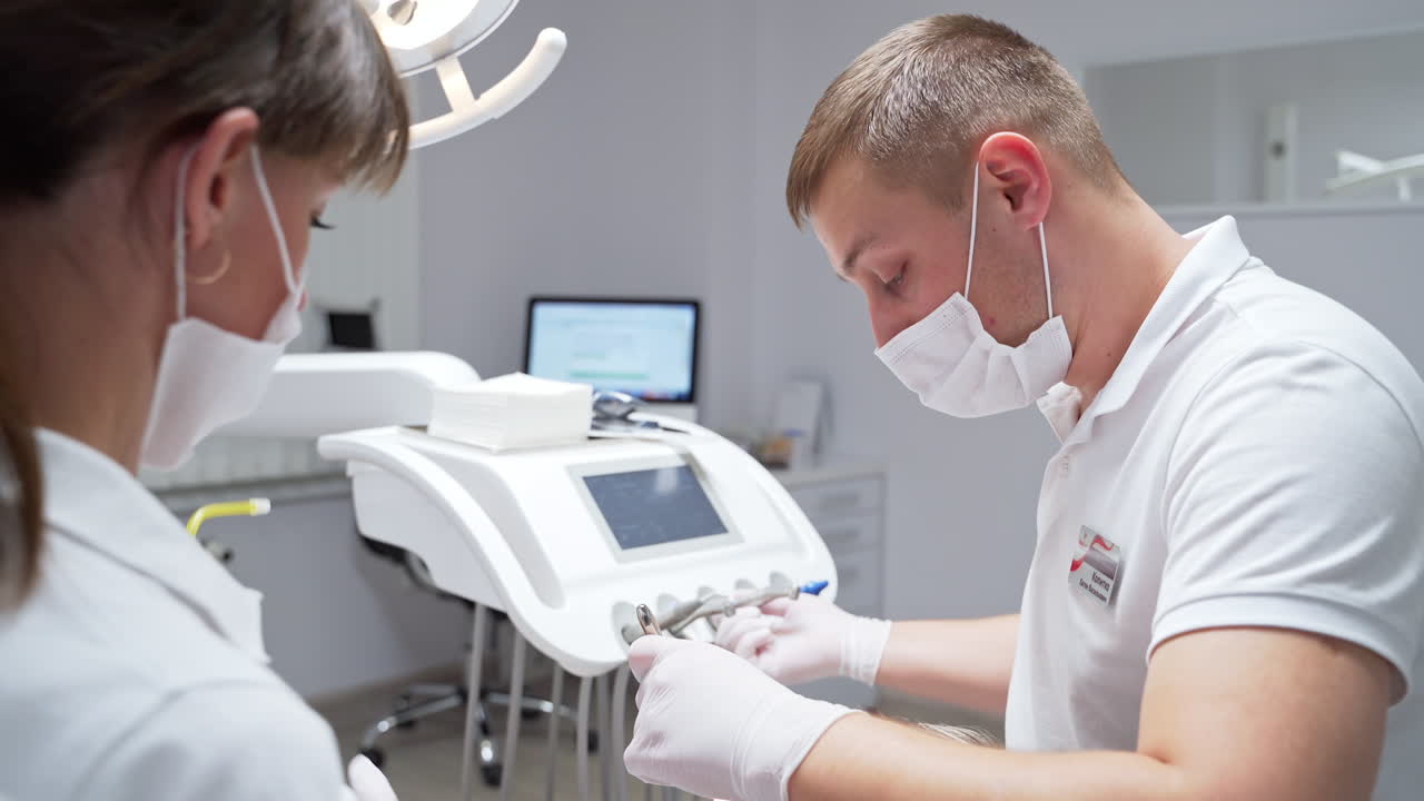 Medica dental care for a patient in modern stomatology clinics. Male dentist and female nurse discuss and comment during their work.