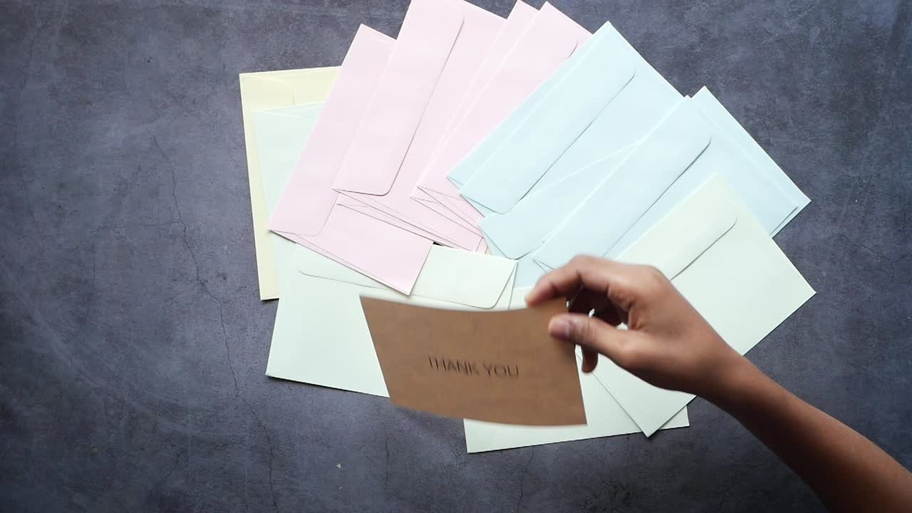봉투 로 둘러싸인 감사 카드 를 들고 있는 손