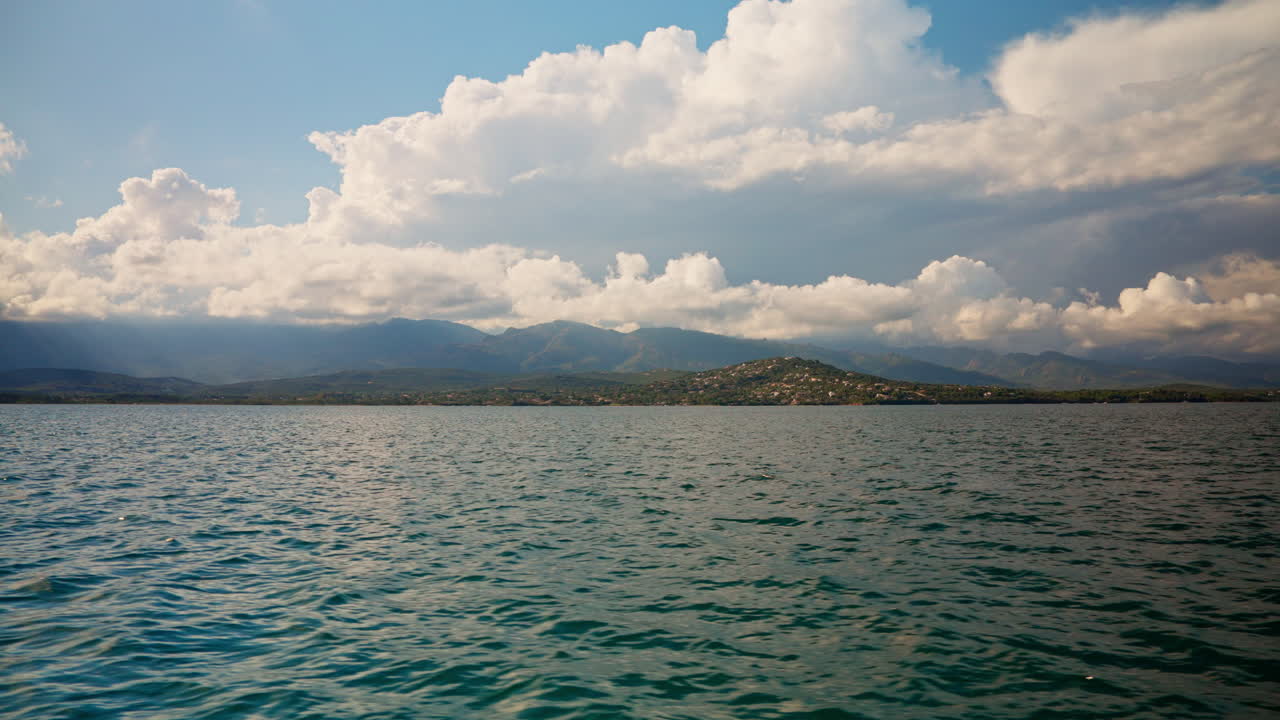 Boat tour along the coastline of Corsica. View of the mediterranean sea. Summer holidays destination. Fluffy clouds in the distance. Island exploration. Peaceful seascape