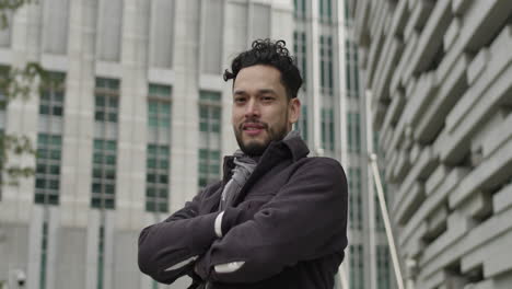 Portrait-of-successful-young-entrepreneur,-dressed-in-autumn-clothes,-looking-at-camera-and-smiling-outdoors-in-downtown-business-district