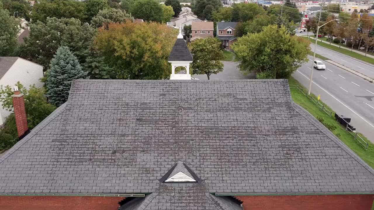 Red brick schoolhouse with bad shingles and a bell tower