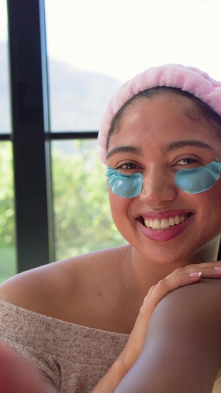 Vertical video: Camera rolling woman resting on pal shoulder at window for spa, pink band blue gels