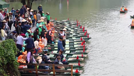 people embarking and disembarking rowboats by a river