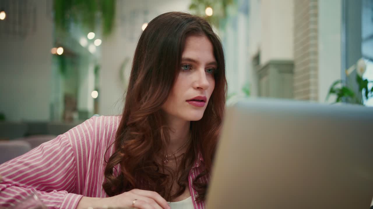 Young Woman Working on Laptop in a Modern Cafe