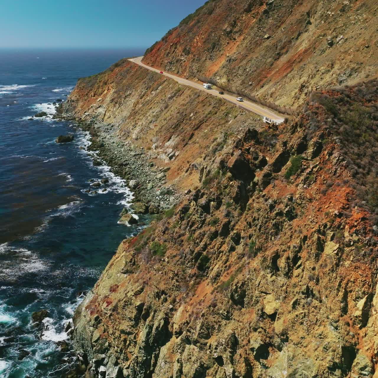 Craggy rugged coastline of California. Dark blue Pacific Ocean with algae accumulation on surface. Top view