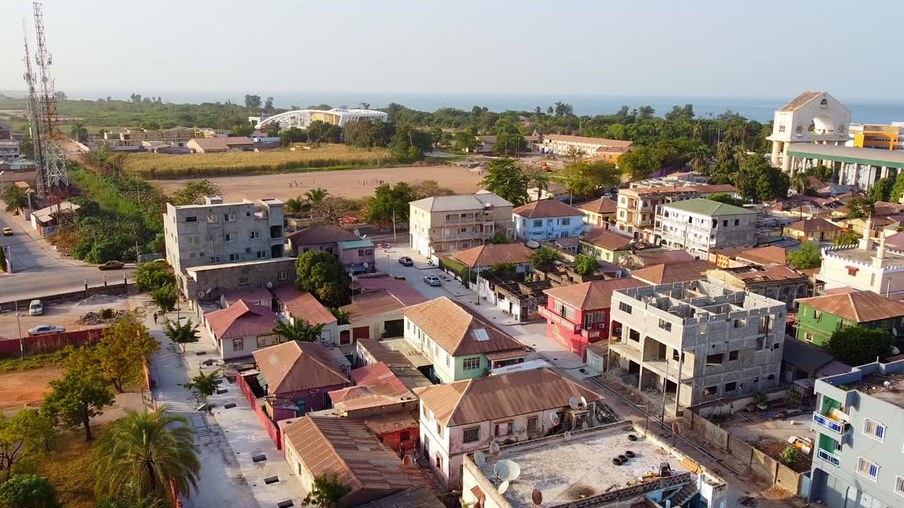 Aerial static establishing view of Banjul city cityscape and Arch 22 on sunny afternoon revealing old architecture, atlantic ocean