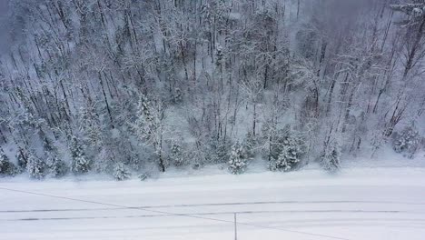 Luftrutsche-Entlang-Einer-Schneebedeckten-Straße-Und-Eines-Waldes-Während-Eines-Schneesturms-Von-Oben-Nach-Unten-In-Zeitlupe