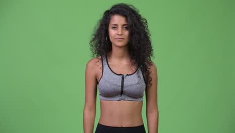 young beautiful hispanic woman with gym clothes pointing up