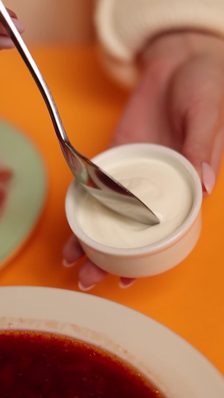 Mulher comendo borscht com creme azedo