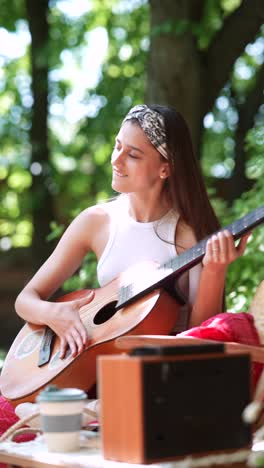 young woman playing acoustic guitar outdoors