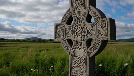 close-up of an ornate celtic cross in a lush green field