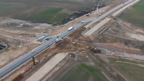 Toma-De-Drones-De-La-Carretera-En-Construcción-Para-El-Proyecto-De-Expansión,-Hay-Un-Enorme-Sitio-De-Construcción-Con-El-Equipo-Para-El-Trabajo.