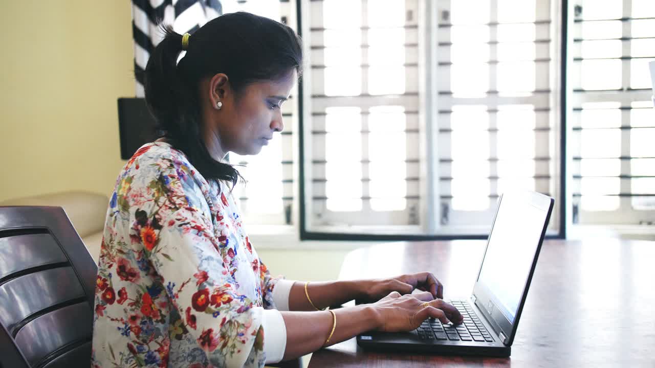 Closeup of an Indian business woman working from home sitting on a table