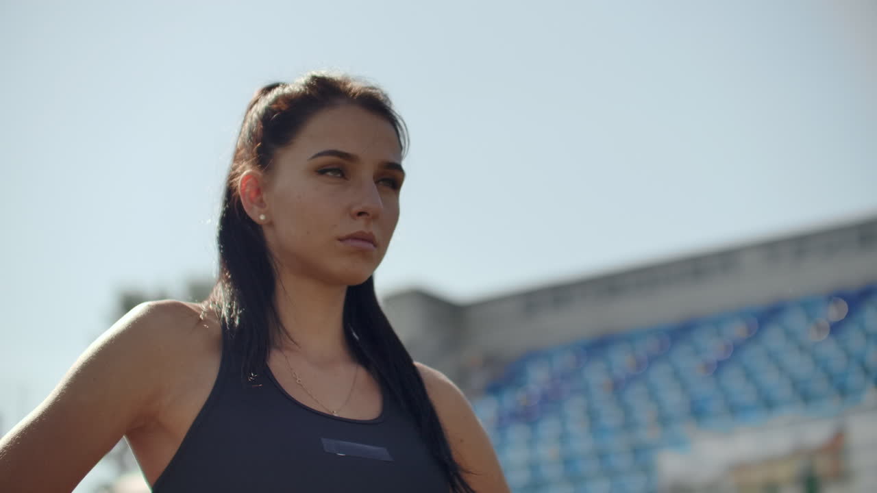 bela atleta no estádio respirando e preparando-se para começar a corrida. motivação e sintonização para a corrida, concentração e atitude