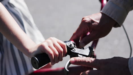 Closeup,-parent-and-child-with-hands-on-bicycle