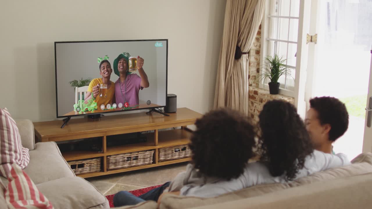 Famiglia afroamericana a casa che usa la smart TV per fare una videochiamata nel giorno di San Patrizio.