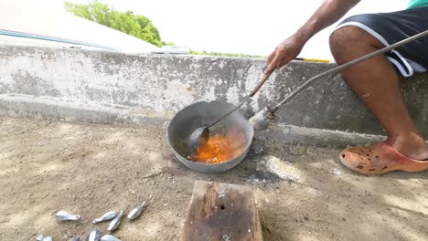 hombre que fundió plomo fundido en un molde al aire libre con cuchara, proceso tradicional de metalurgia, día soleado