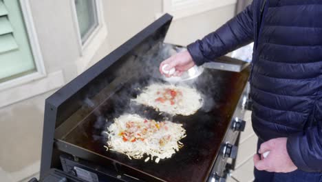 cracking eggs on the potatoes to make hash brown omelets