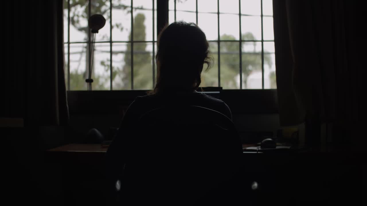 4K at 24fps - Woman on the computer on a rainy day with backlight - Mistery mood