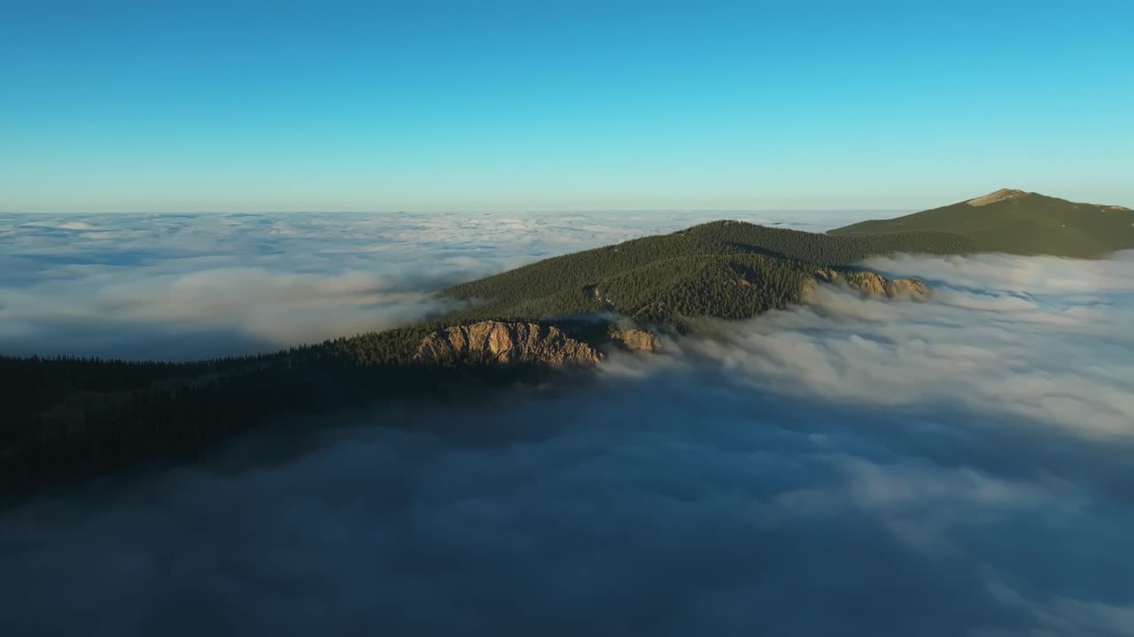 Morning light breaks through fog above Juniper Pass Colorado mountain ridges, ethereal atmospheric, panoramic aerial
