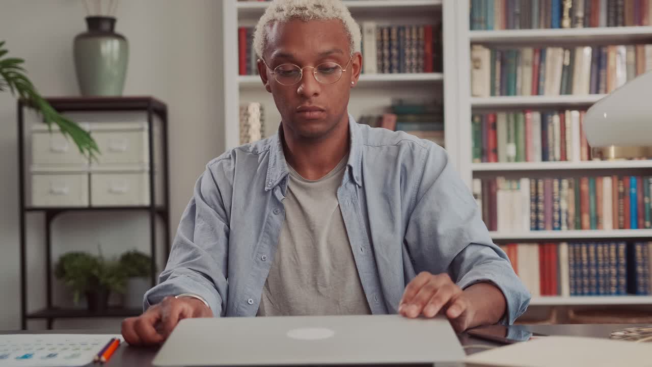 Confident african man opens up modern laptop and starts his work day remotely