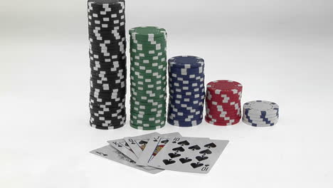 stacks of poker chips sit in a row arranged by value behind a deck of playing cards