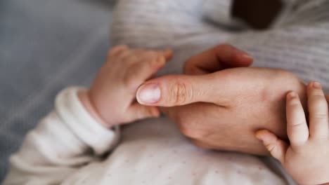 closeup of baby grabbing moms arm and finger