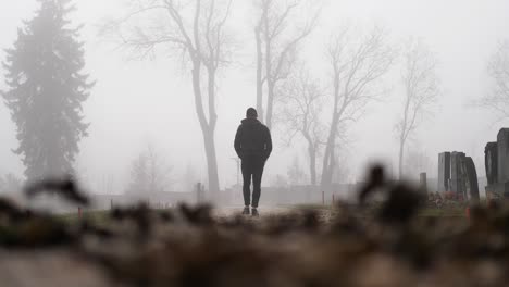 slow motion of man walking in graveyard in fog