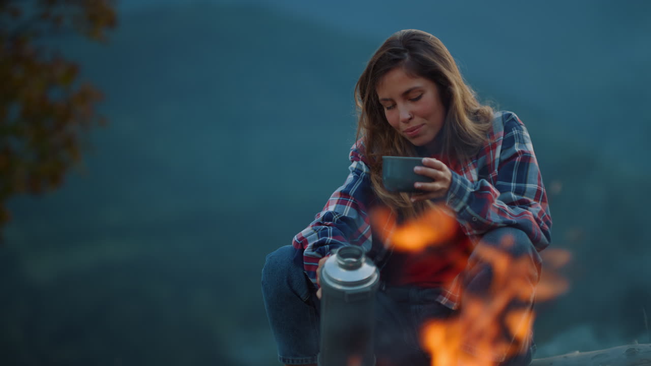 mujer hermosa en primer plano en el campamento en una noche relajante. chica feliz bebiendo té afuera.