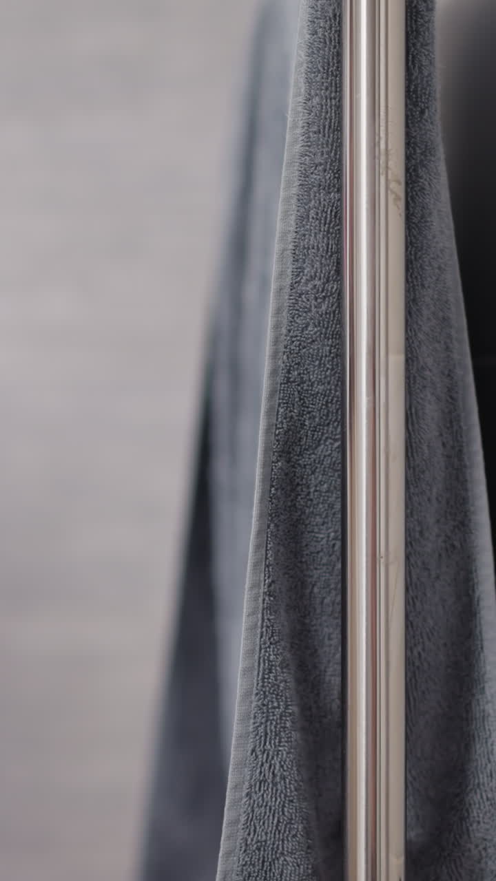 mujer con túnica de peluche se seca la mano con una toalla colgada en la barandilla en el baño. mujer se sacude la mano húmeda limpiándose con una toallina en un baño espacioso en cámara lenta