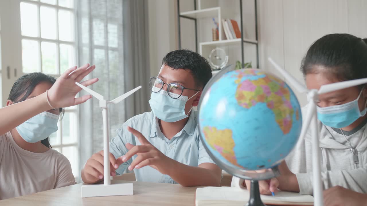 Asian Kids Are Wearing Facemasks Learning About Ecology Problems And Their Solution With Wind Turbine Model And Globe At School