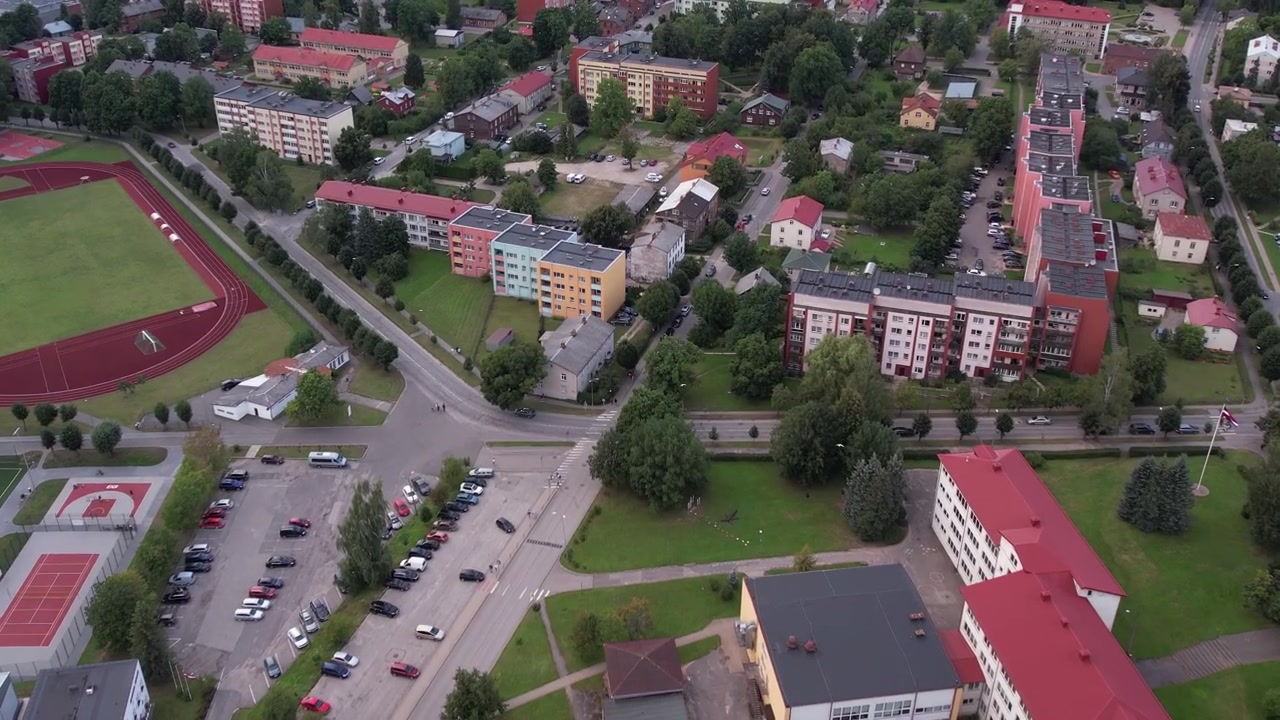 Un drone cattura una vista panoramica della città di Limbaži in estate. Gli edifici, le strade e la vegetazione circostante della città sono bagnati dalla luce del sole, mostrando un'atmosfera vibrante e pacifica
