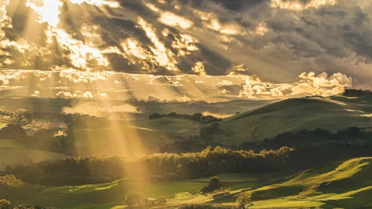 Aerial video view of sunlit rolling hills under dramatic clouds, capturing a serene landscape