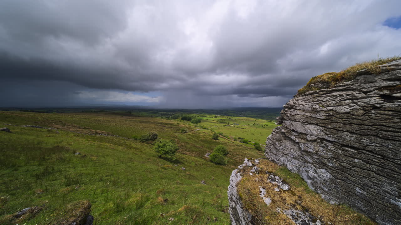 Timelapse af landskabsdal på landet med en forbipasserende regnstorm, massiv klippeblok, bakker og sø i det fjerne på en overskyet, solrig forårsdag, set fra Carrowkeel i County Sligo i Irland.